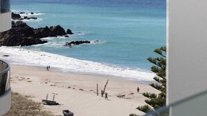 Ein Strand mit Felsen, sandigem Ufer und einigen Spaziergängern.