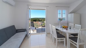 A modern, well-lit room with a balcony, a dining area with white furniture, and a view of the landscape. - Stunning apartment in Milna with WiFi (Milna)