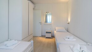 A small, clean room with two single beds, a wardrobe, a small table, and a mirror. - Stunning apartment in Milna with WiFi (Milna)