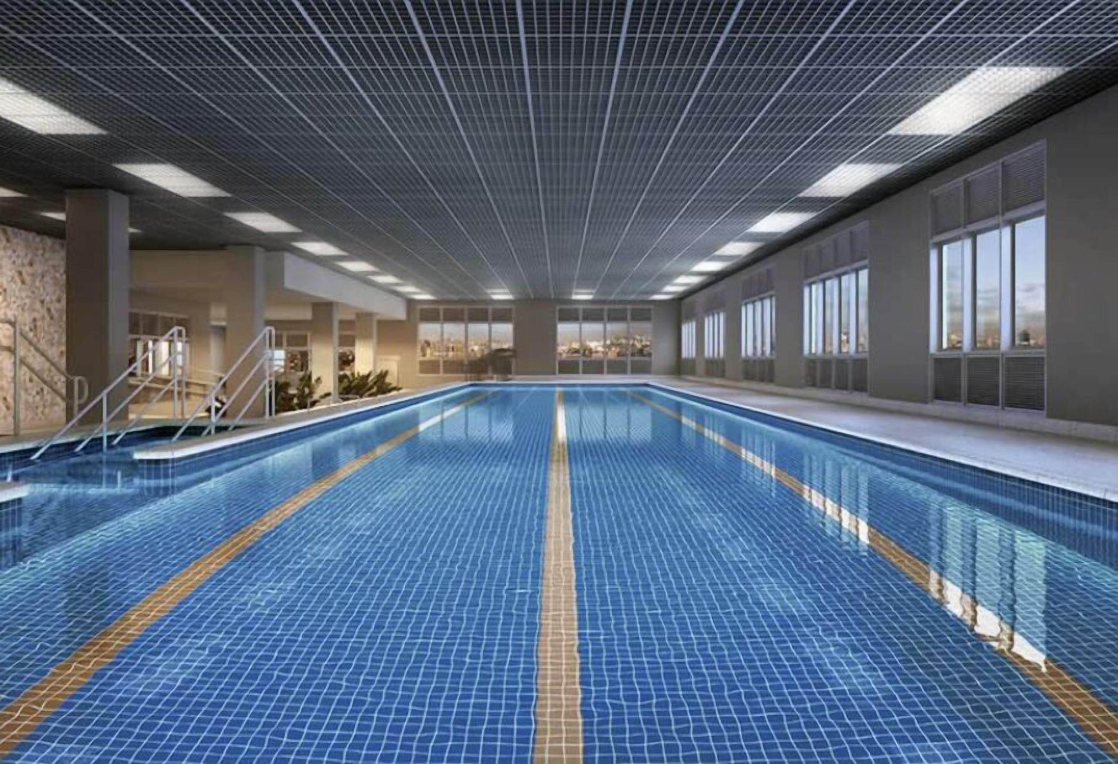 A large indoor swimming pool with clear lanes, a tiled floor, and a grid-patterned ceiling.