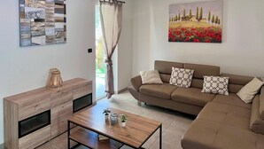 Una sala moderna con un mueble de madera, un sofá marrón con cojines estampados, una mesa de centro y un cuadro de un paisaje.