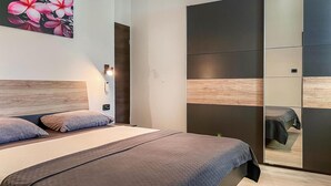 Un dormitorio moderno con una cama grande, cabecera de madera, un espejo y un armario con diseño de paneles de madera.