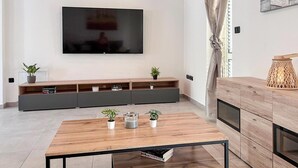 Una sala de estar moderna con un televisor de pantalla plana montado en la pared, una mesa de centro de madera y un mueble empotrado con estantes y armarios.