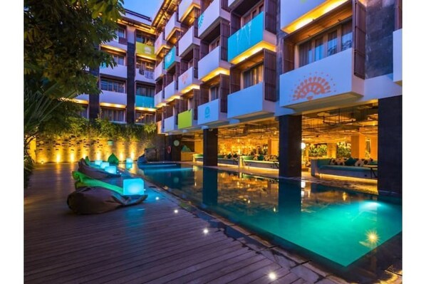 Experience the hotel's sleek, multi-story design with a pool and comfortable outdoor seating.