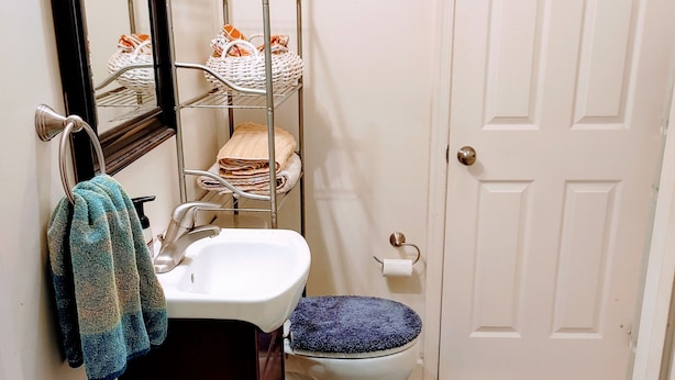 A bathroom with a sink, toilet, and a metal shelf with towels. - Hidden Gem on Hidden Valley Lane (Linden)