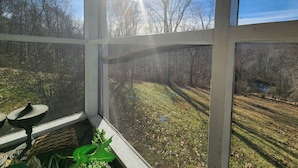 A room with a large window overlooking a grassy area and trees.