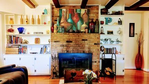 A cozy living room with a fireplace, bookshelves, and a coffee table with decorative items.