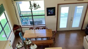 Una cocina amplia con una gran mesa de madera, una mesa más pequeña con taburetes y una lámpara colgante.