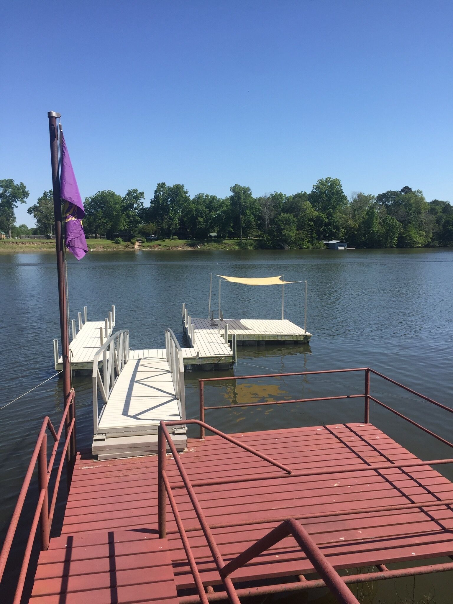 Un muelle con una bandera morada, un toldo blanco y una plataforma roja.