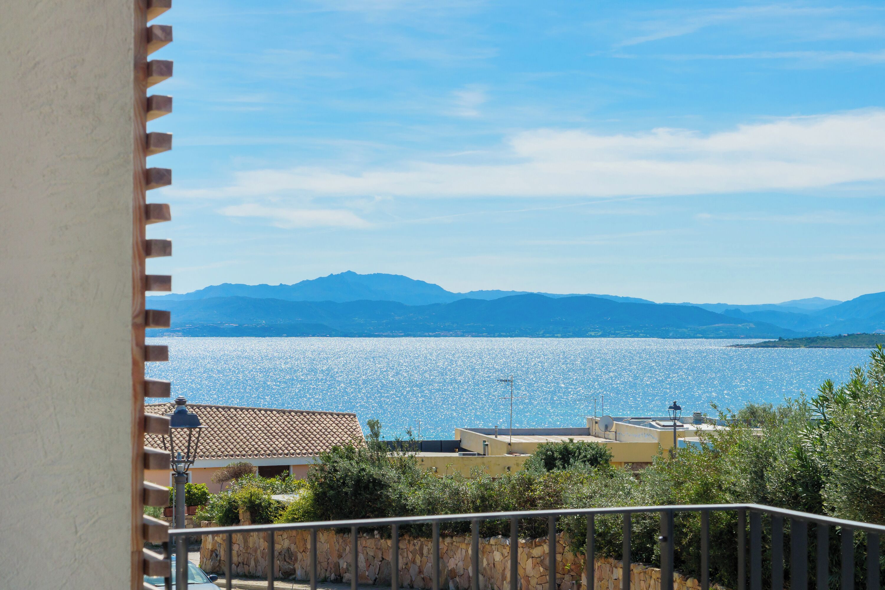 Un balcón con vista a un mar tranquilo y montañas lejanas.