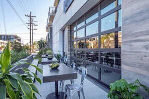 Dine al fresco in a tranquil outdoor space surrounded by lush greenery and city views.