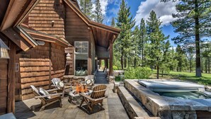 Una cabaña de troncos con un hogar de piedra, asientos exteriores y un jacuzzi.