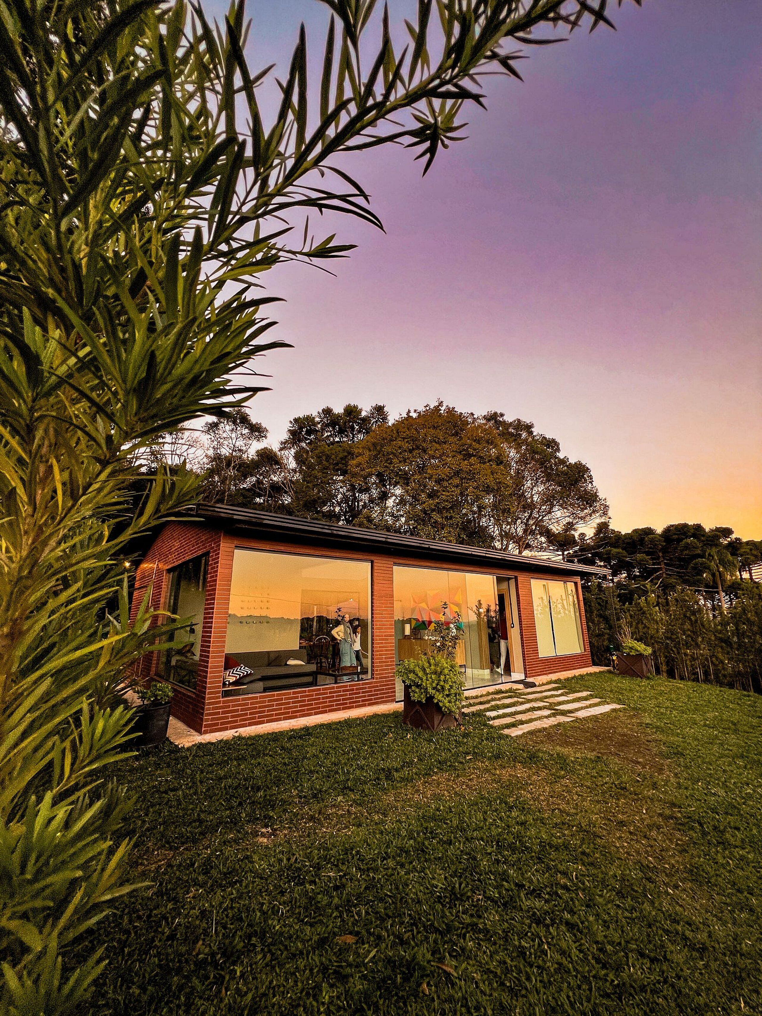 A modern house with large windows, a brick exterior, and a well-maintained lawn.