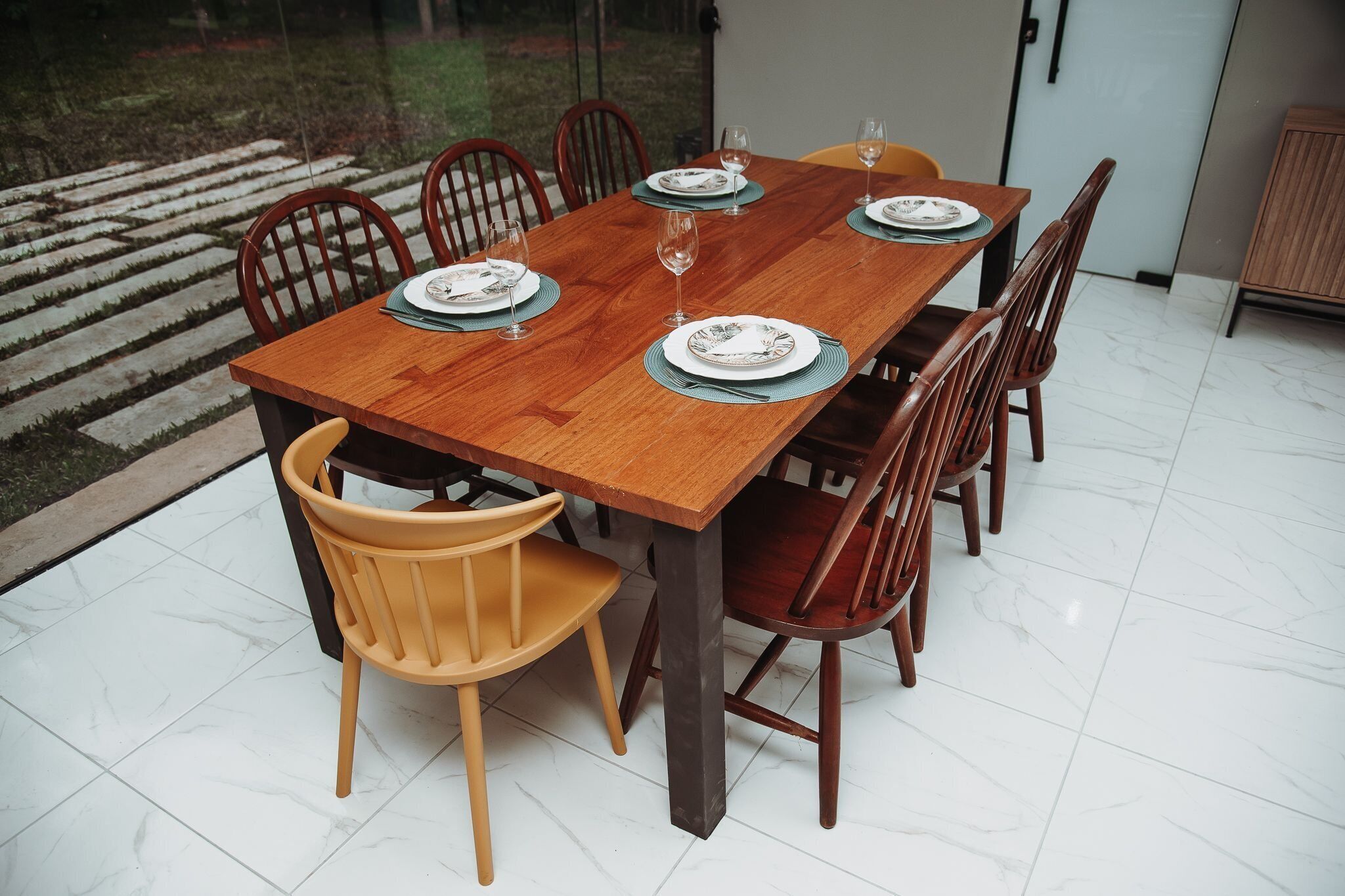 A dining table set with plates, glasses, and cutlery, surrounded by chairs.