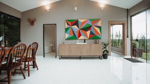 Un comedor espacioso con techo alto, una cocina moderna con encimera de madera y un cuadro abstracto grande en la pared.