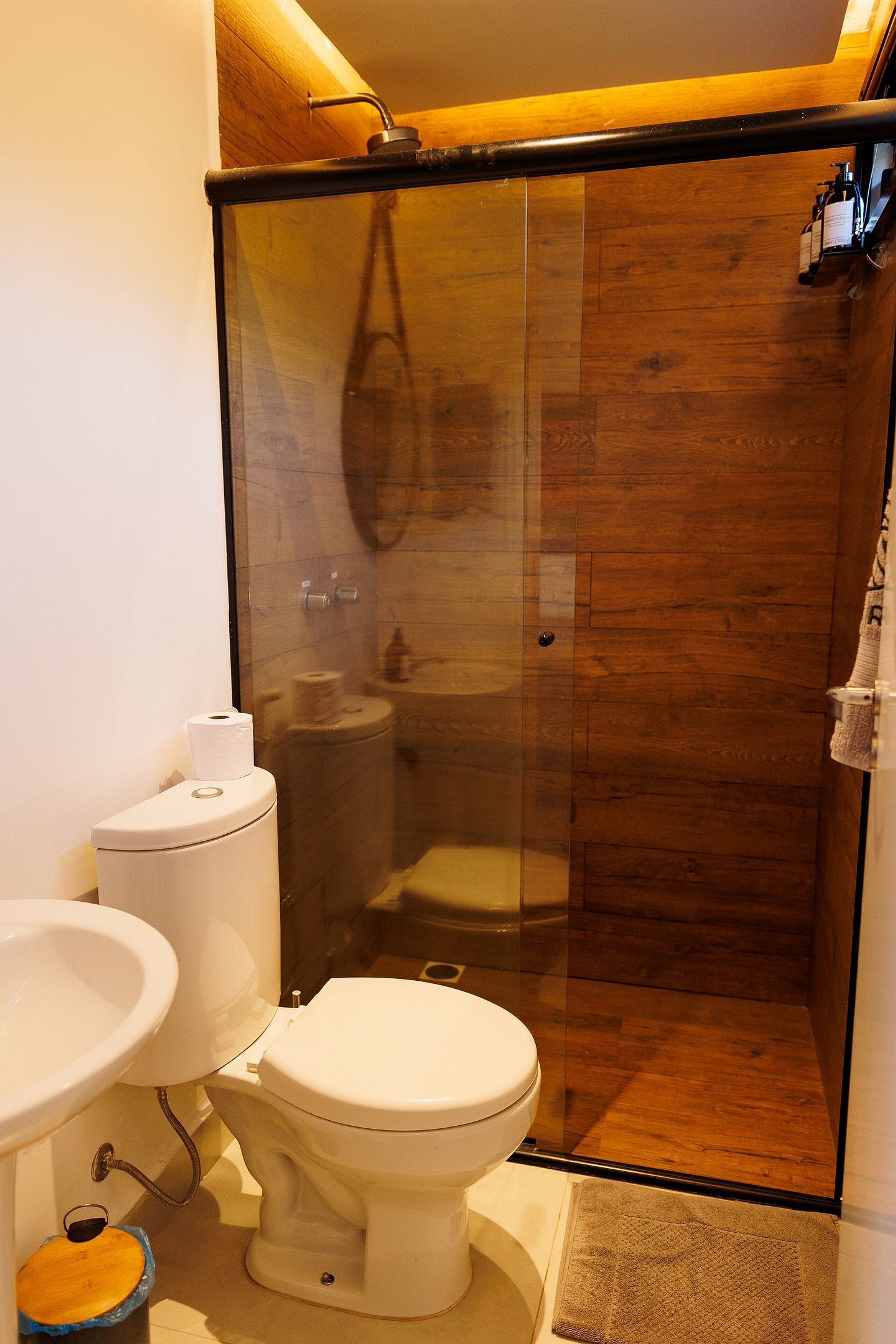 A bathroom with a toilet, sink, and shower enclosure.