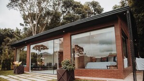 A modern house with large glass windows, a brick exterior, and a grassy yard. - Reserva Cabanas (Balsa Nova)