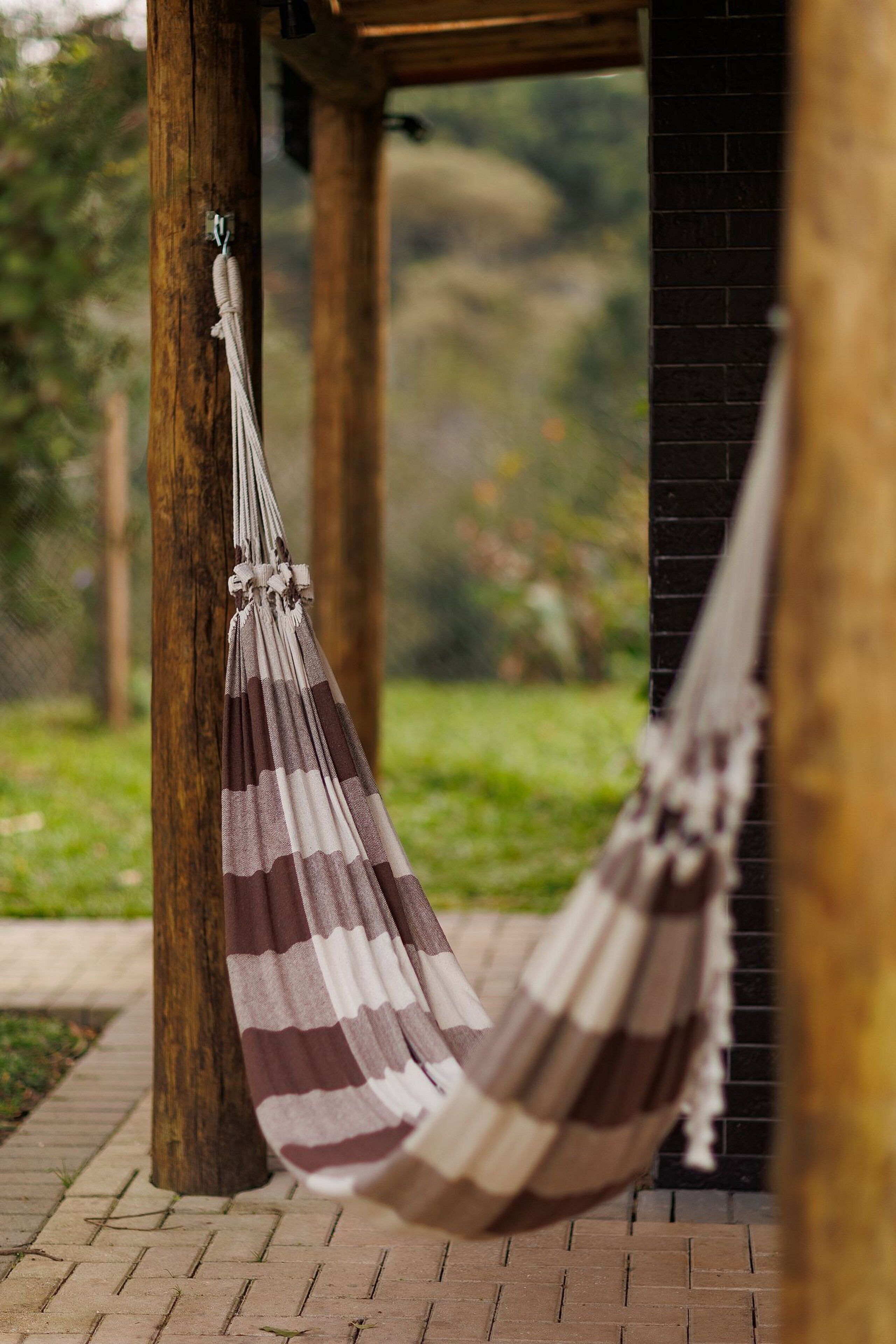 A hammock hanging between wooden pillars in an outdoor setting.