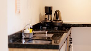 Una cocina con estufa, cafetera y hervidor.