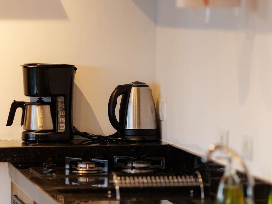 Una cucina con una macchina da caffè, un bollitore e una bottiglia d'olio sul piano di lavoro.