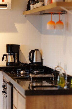 A kitchen with a coffee maker, a kettle, and a bottle of oil on the counter. - Reserva Cabanas (Balsa Nova)
