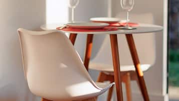 A dining area with modern chairs and a round table, wooden flooring, and a view of the outdoors.