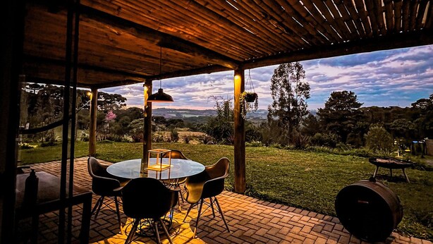 An outdoor patio with a brick floor, wooden pergola, and a table with chairs. - Reserva Cabanas (Balsa Nova)