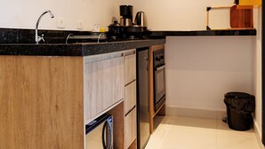 Una cocina compacta con armarios de madera, horno empotrado, cafetera y microondas.