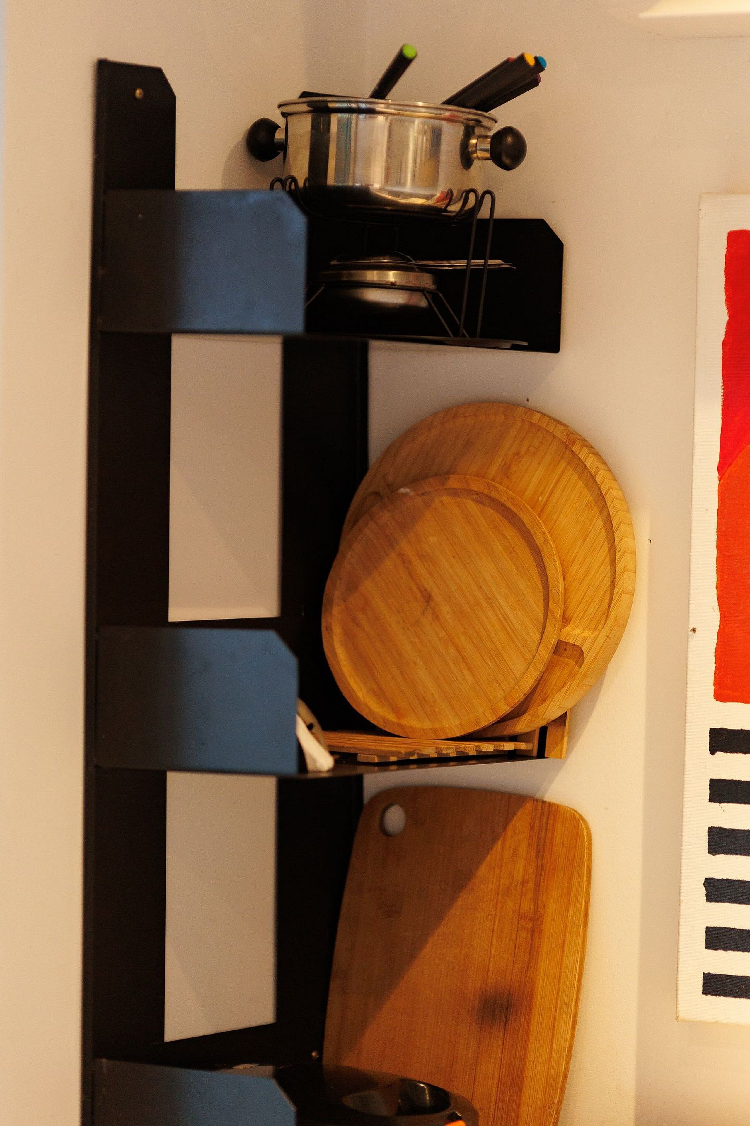 Un coin cuisine avec une casserole sur la cuisinière, une planche à découper en bois et un saladier en bois.