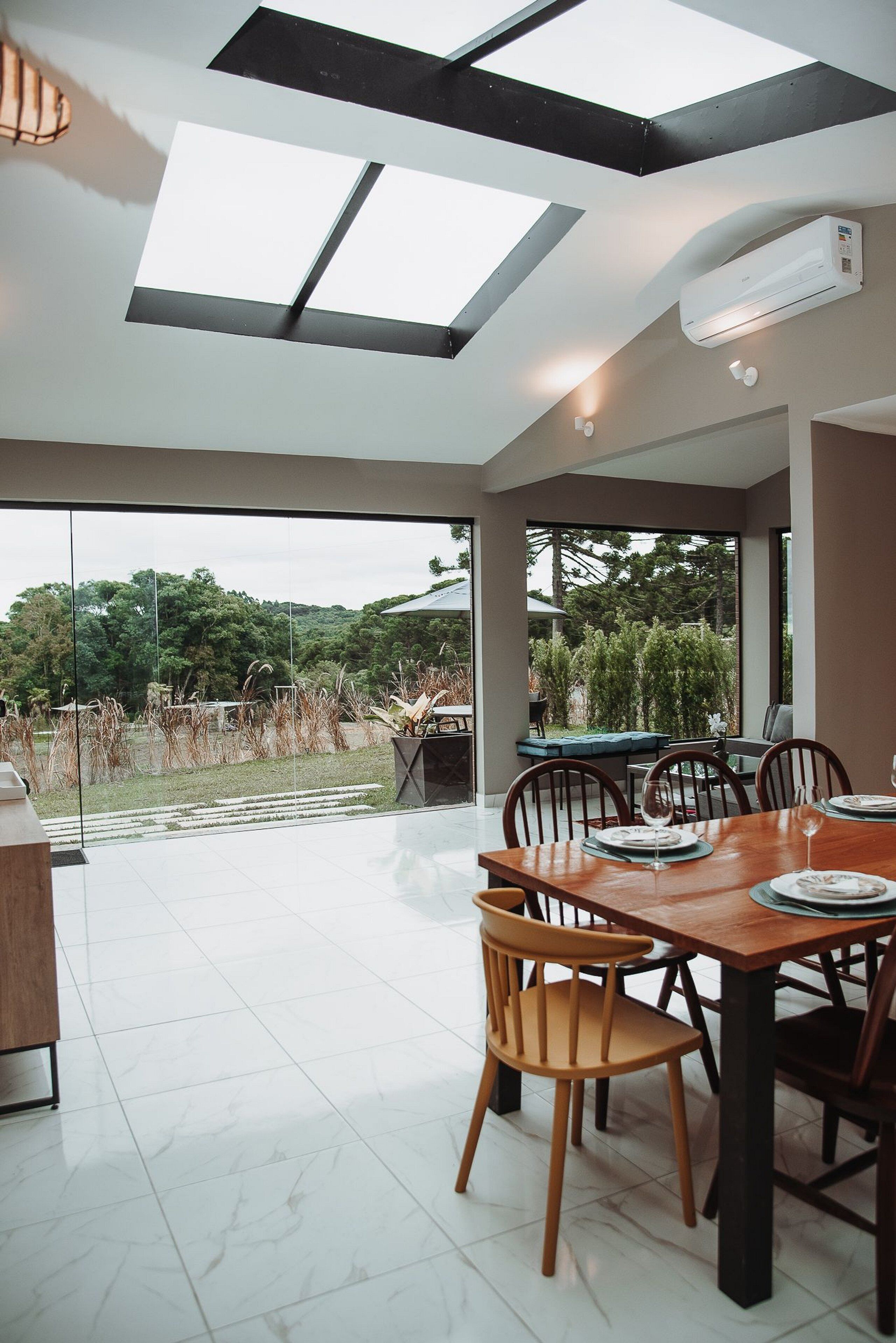 A dining area with a table set for four, large windows, and a view of the outdoors.