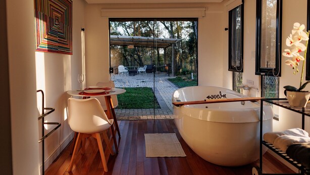 Un baño moderno con bañera, puerta de vidrio que da a un patio exterior y comedor con sillas y mesa.