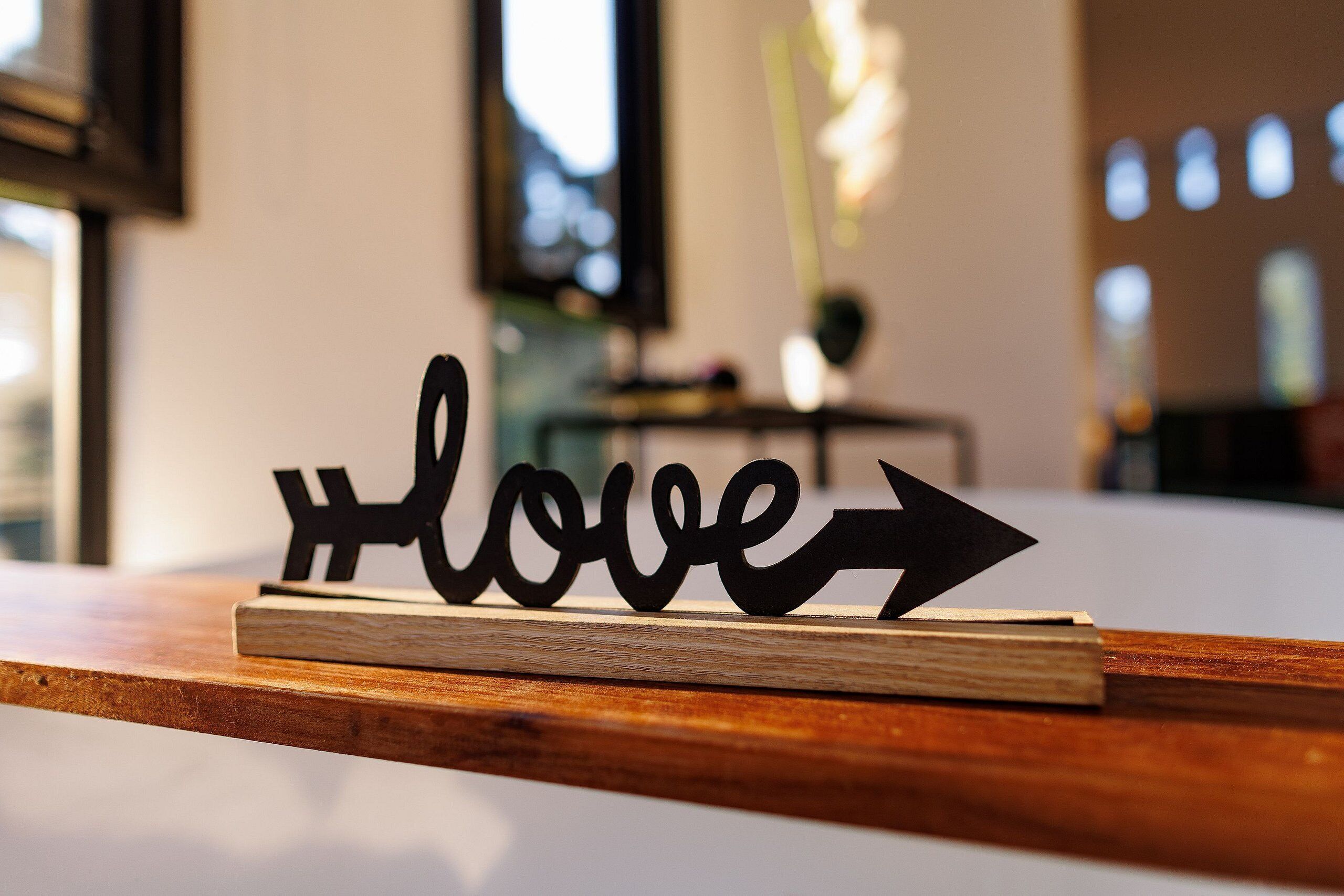 A wooden shelf with a metal sign that reads '+love' with an arrow pointing to the right.