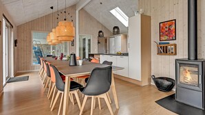 A modern kitchen with wooden cabinets, a dining area with a large table and chairs, a built-in stove, and a skylight. - Gorgeous home in Glesborg with sauna (Glesborg)