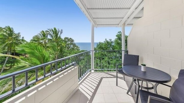 A balcony with a view of the sea, a table, and chairs. - Amaroo at Trinity - Classic Ocean View Studio (Cairns)