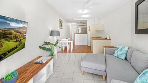 Een moderne woonkamer met een grijze bank, een houten bijzettafeltje en een groot landschapsprent.
