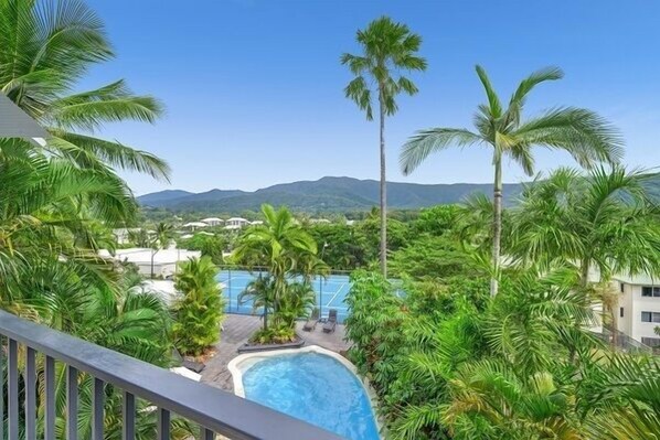 Relax by the pool surrounded by lush greenery and palm trees.