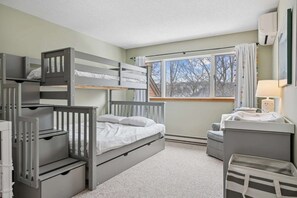 A bunk bed room with a desk, a lamp, and a window with curtains. - End-Unit Condo with Sauna & Pool, Deere Run (Quechee)