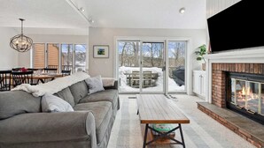 Ein modernes Wohnzimmer mit Kamin, Essbereich und Blick durch Glastüren.