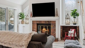 Ein Wohnzimmer mit Kamin, Fernseher und einer gemütlichen Sitzecke.