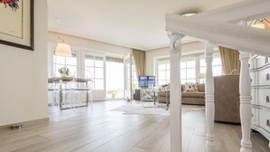 A spacious living area with a dining table, chairs, a sofa, and a TV. - Alte Mühle, Whg. 12 Polo Suite - Alte Mühle (Sylt-Ost)