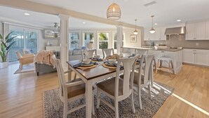 A spacious kitchen with white cabinetry, a dining area with a wooden table and chairs, and a large window providing natural light.