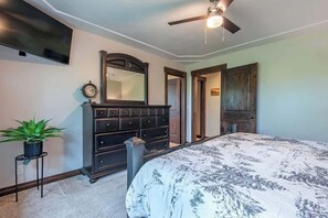 Ein Schlafzimmer mit Bett, Kommode, Spiegel und Deckenventilator.