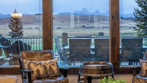 Un espace extérieur accueillant, avec des fauteuils en cuir et une table en bois rustique, offrant une vue imprenable sur un paysage montagneux.