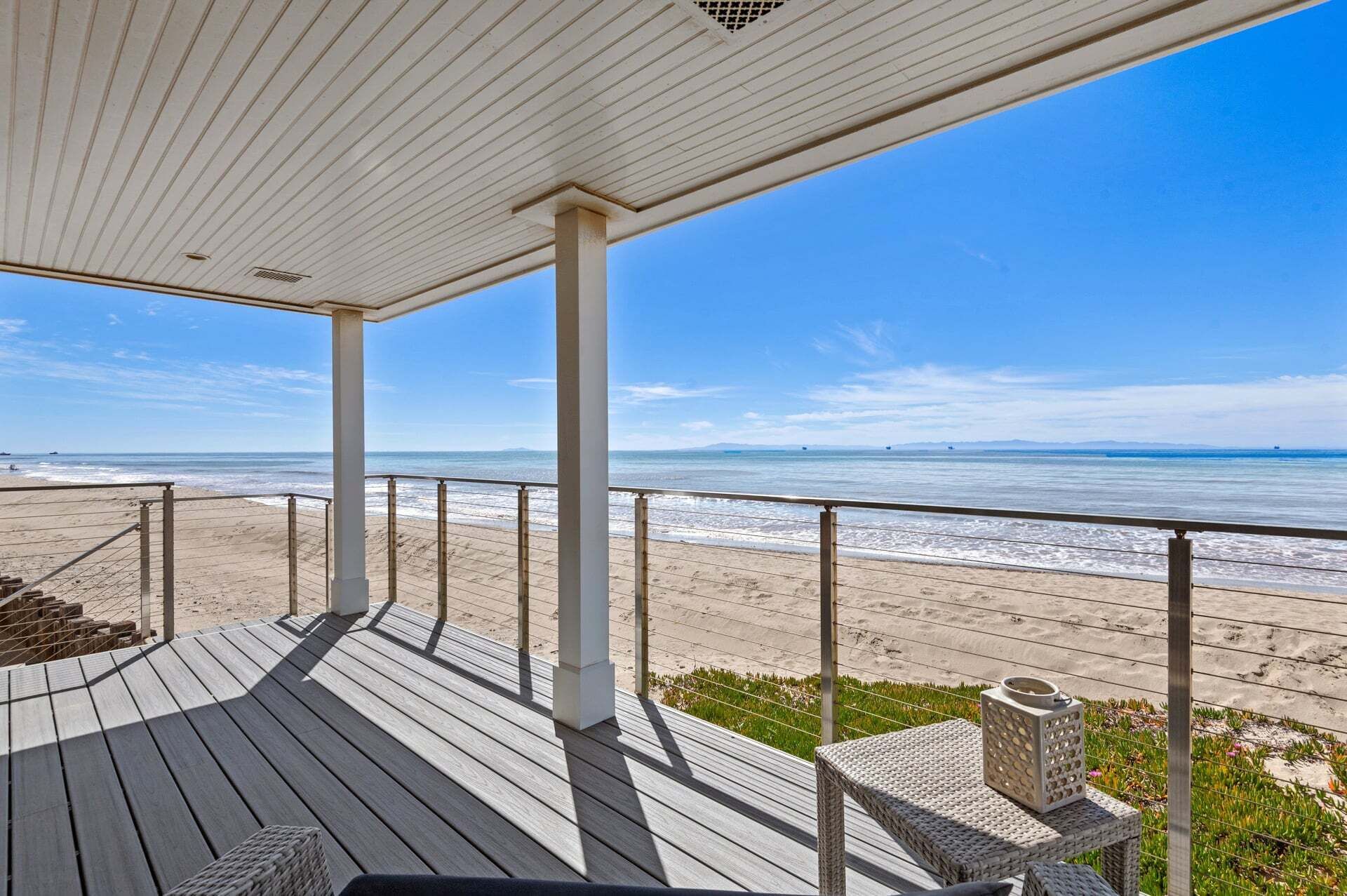 A wooden deck with a view of the beach and ocean.