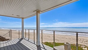 A wooden deck with a view of the beach and ocean.
