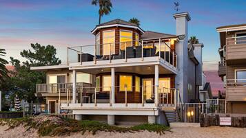 Une maison de deux étages située en bord de mer, dotée d’un balcon, d’une terrasse couverte et offrant une vue sur l’océan.