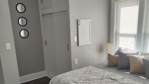 Un dormitorio con una cama, una ventana con persianas, una puerta y tres espejos redondos en la pared.