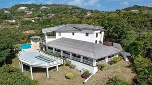 A large white house with a swimming pool, surrounded by lush greenery and hills. - Tamarind Villa - Sprawling 7 bedroom villa (Cap Estate)