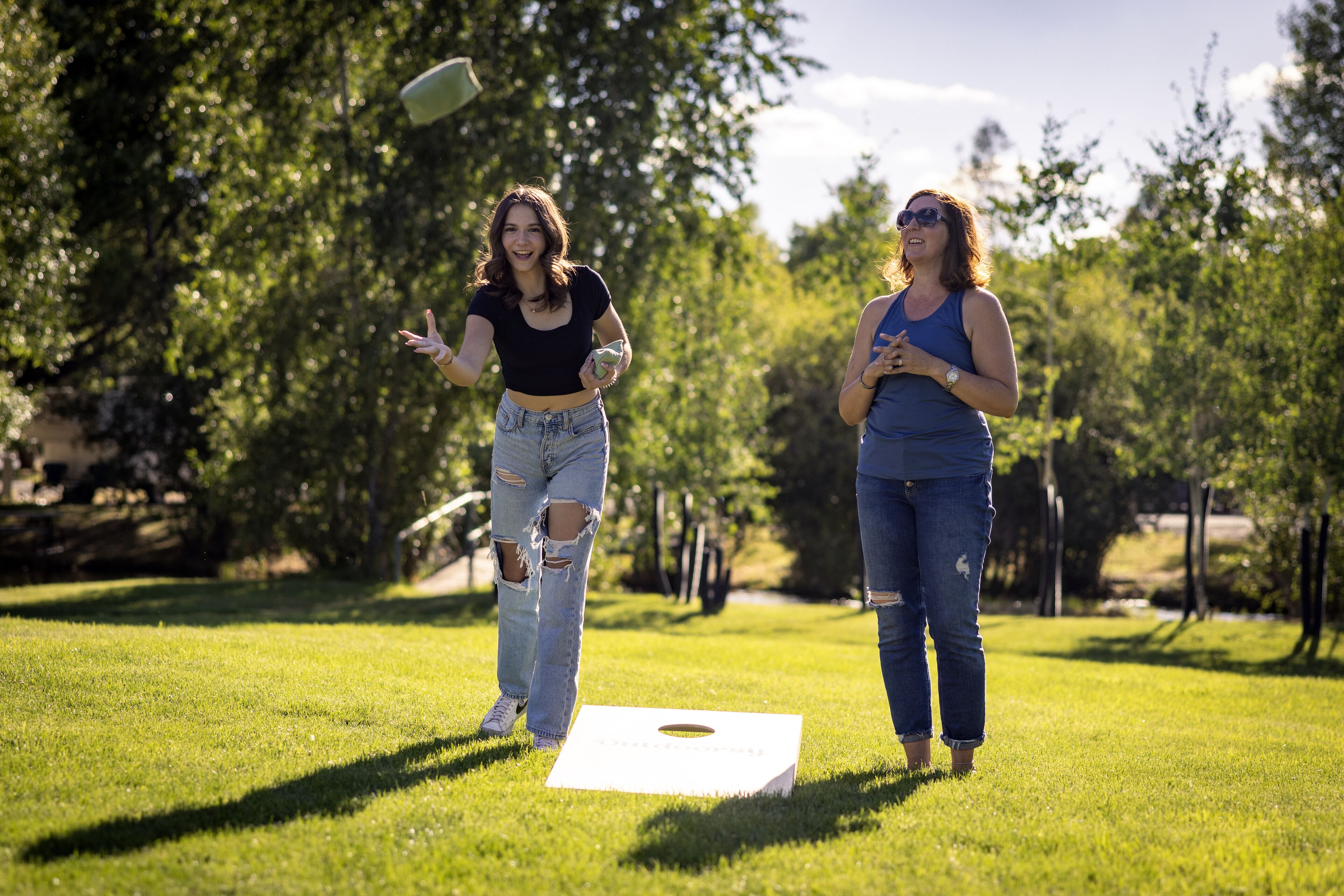 Two people playing a game on a grassy field with trees in the background.