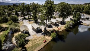 A campsite with several tents and RVs by a river, surrounded by trees. - Outdoorsy Bayfield (Bayfield)